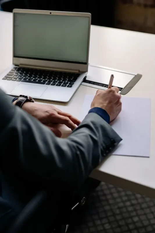 Professional preparing written documents beside a laptop
