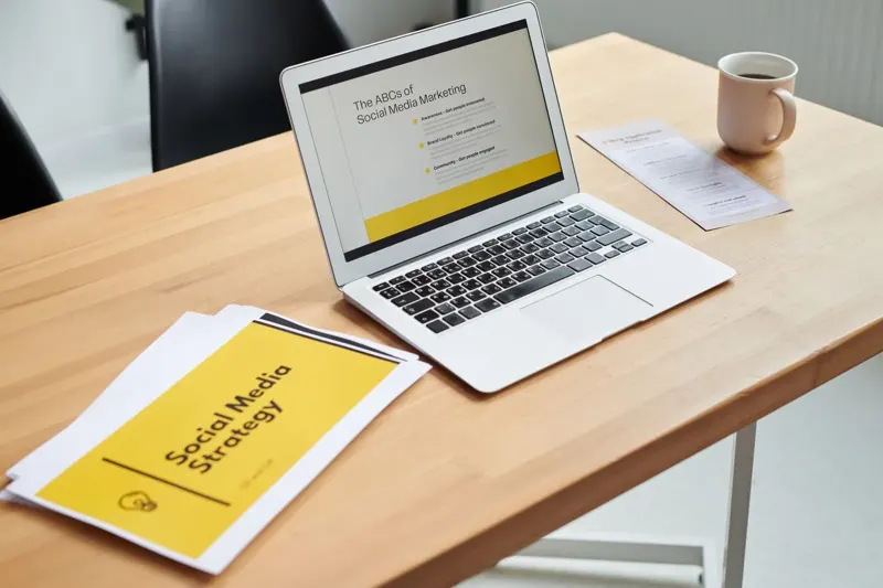 Laptop displaying a social media marketing strategy beside planning documents